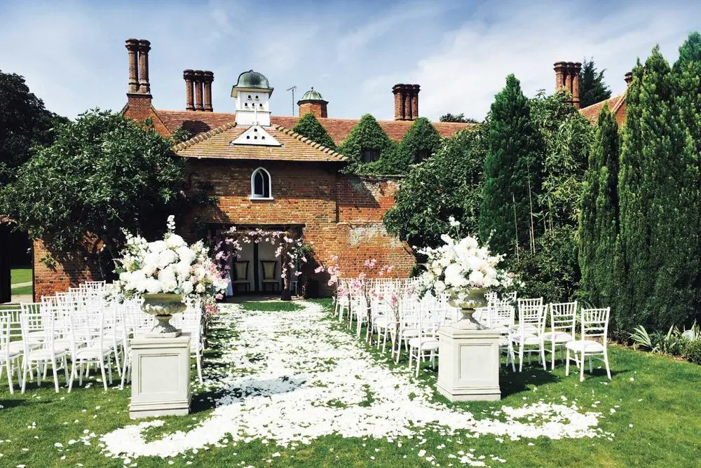 Outdoor ceremony rose petal strewn aisle white chairs