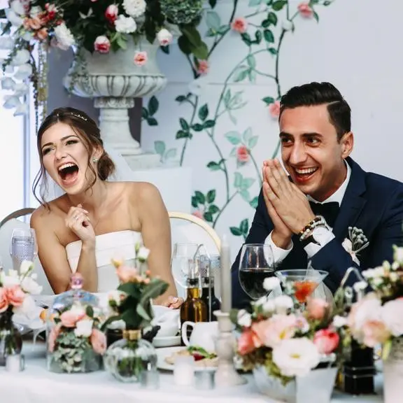 Bride and groom smiling and laughing at their wedding reception.
